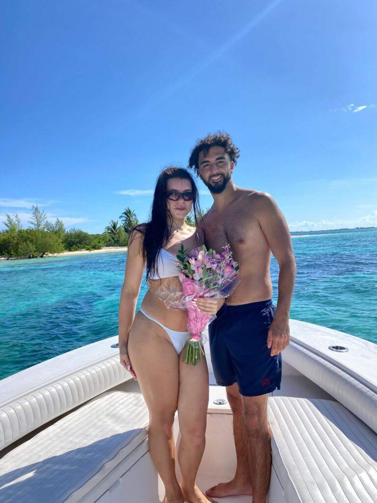 Couple enjoying a sunny day on a boat in clear blue waters.